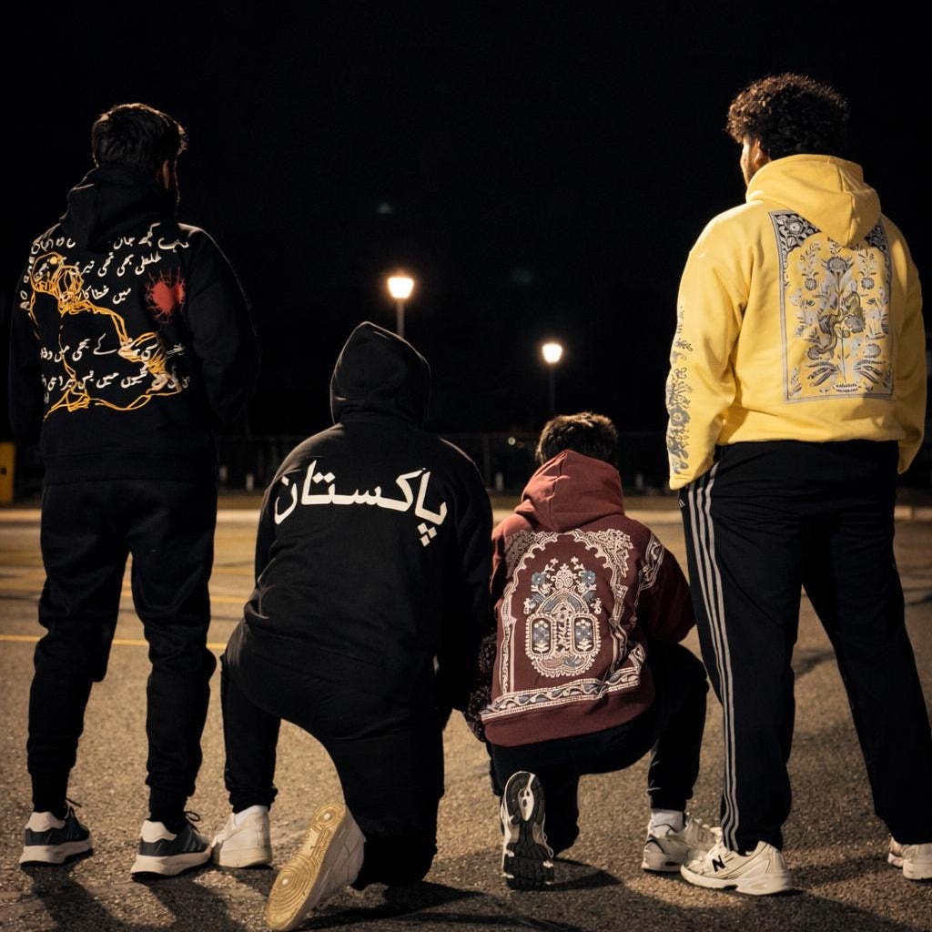Four people standing on a street at night, wearing hoodies with unique designs.